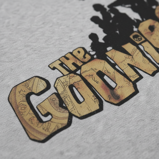 Gray t-shirt with 'The Goonies' logo on a white background Close-up detail of logo